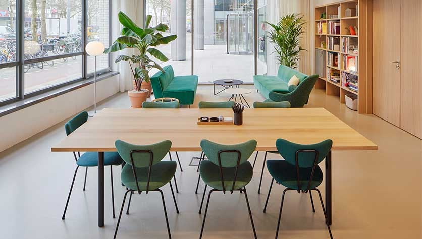 Grüne Stühle in wunderschönen Büroräumen für einen Blogpost zur Verschönerung deines Arbeitsplatzes